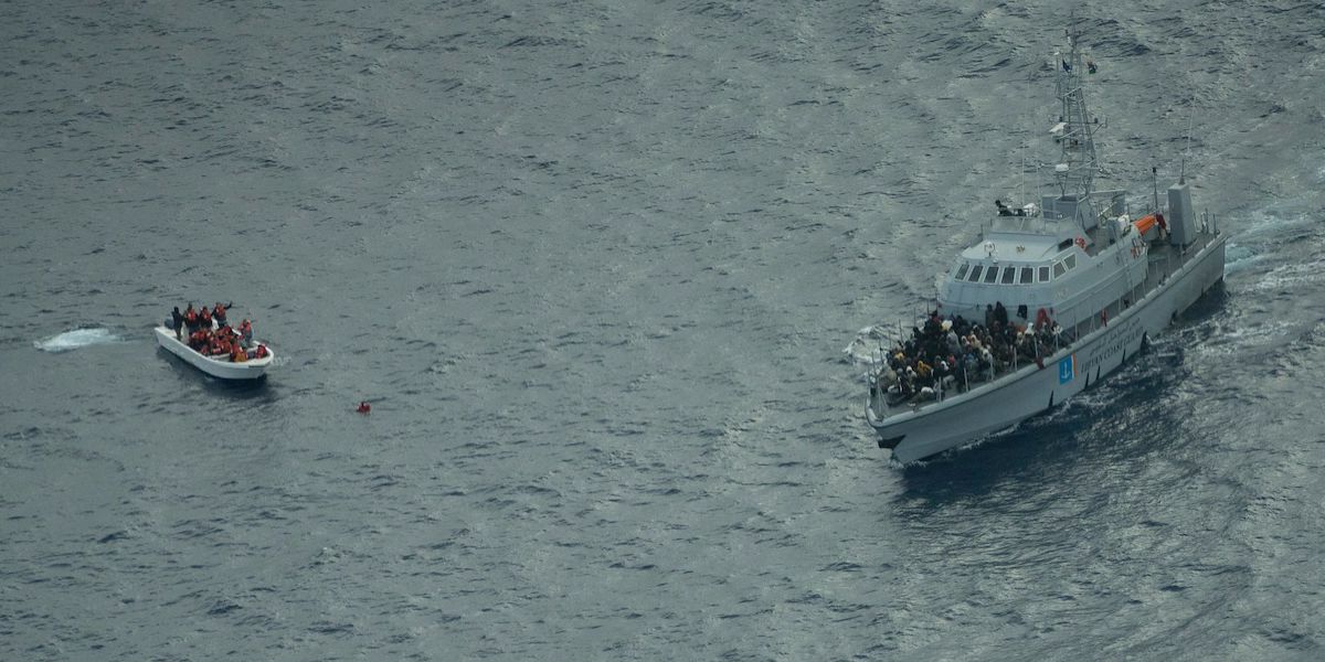 Una motovedetta della cosiddetta Guardia costiera libica, in mare vicino a un'imbarcazione di migranti, fotografata dall'alto