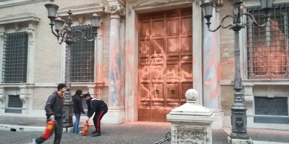 tre attivisti di ultima generazione imbrattano la porta di palazzo madama con della vernice arancione
