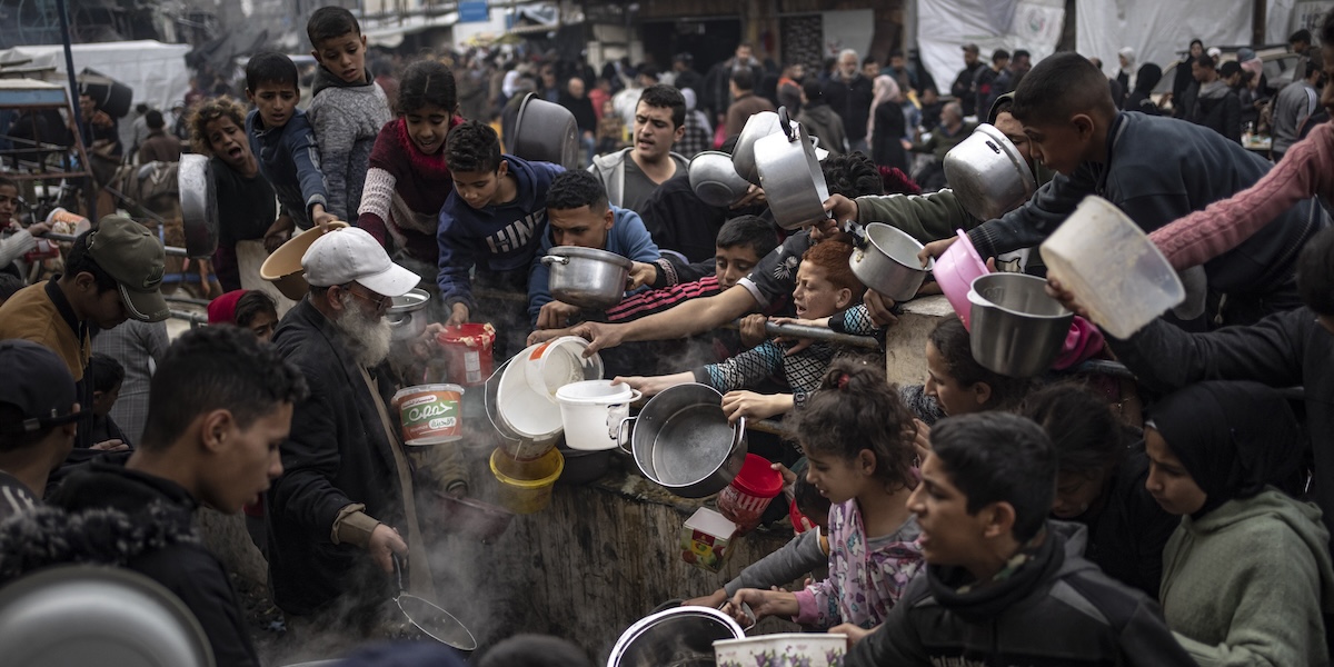 Persone palestinesi aspettano di ricevere cibo a Rafah, nella Striscia di Gaza, lo scorso 23 dicembre