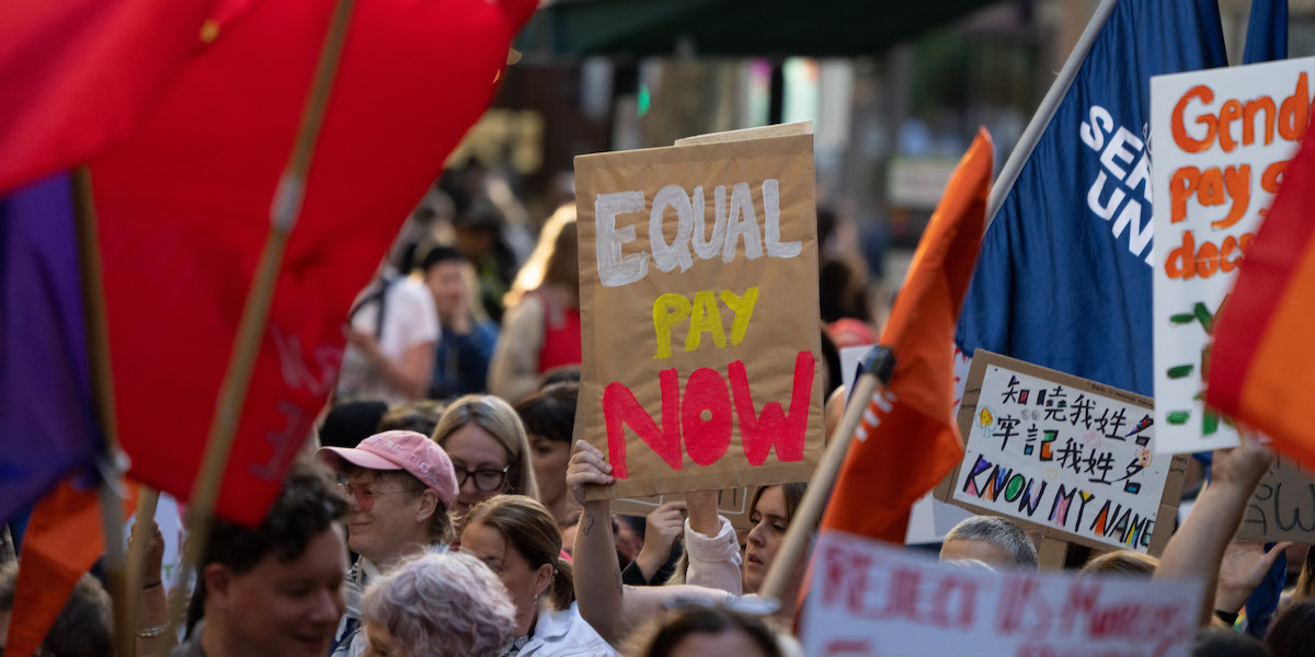 Foto di un cartello con scritto "Equal pay now", durante una manifestazione femminista