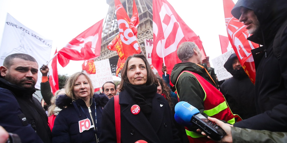 sophie binet in mezzo a una folla con bandiere rosse della cgt, davanti alla tour eiffel