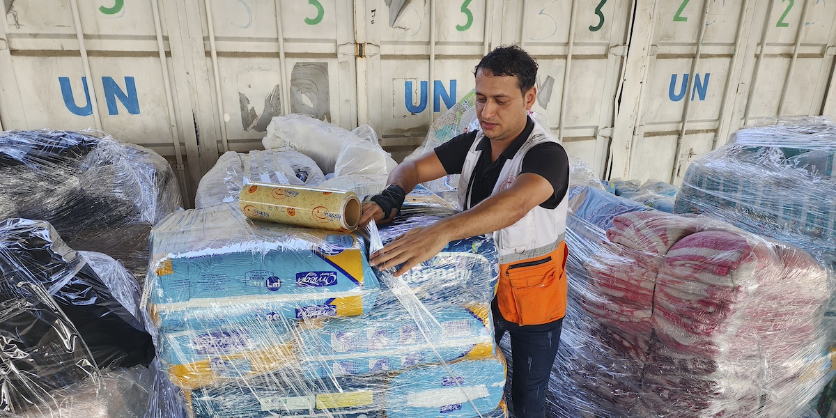 Un operatore delle Nazioni Unite prepara gli aiuti da distribuire ai palestinesi nel magazzino dell'UNRWA a Deir Al-Balah, nella Striscia di Gaza