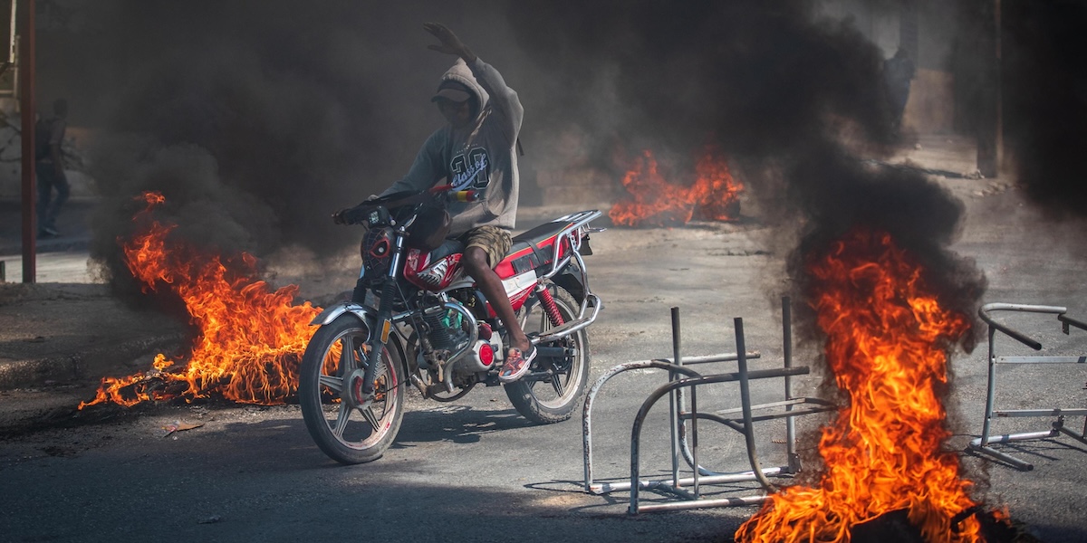 Una persona attraversa una barricata e oggetti incendiati a bordo di una moto a Port-au-Prince, Haiti, primo marzo 2024