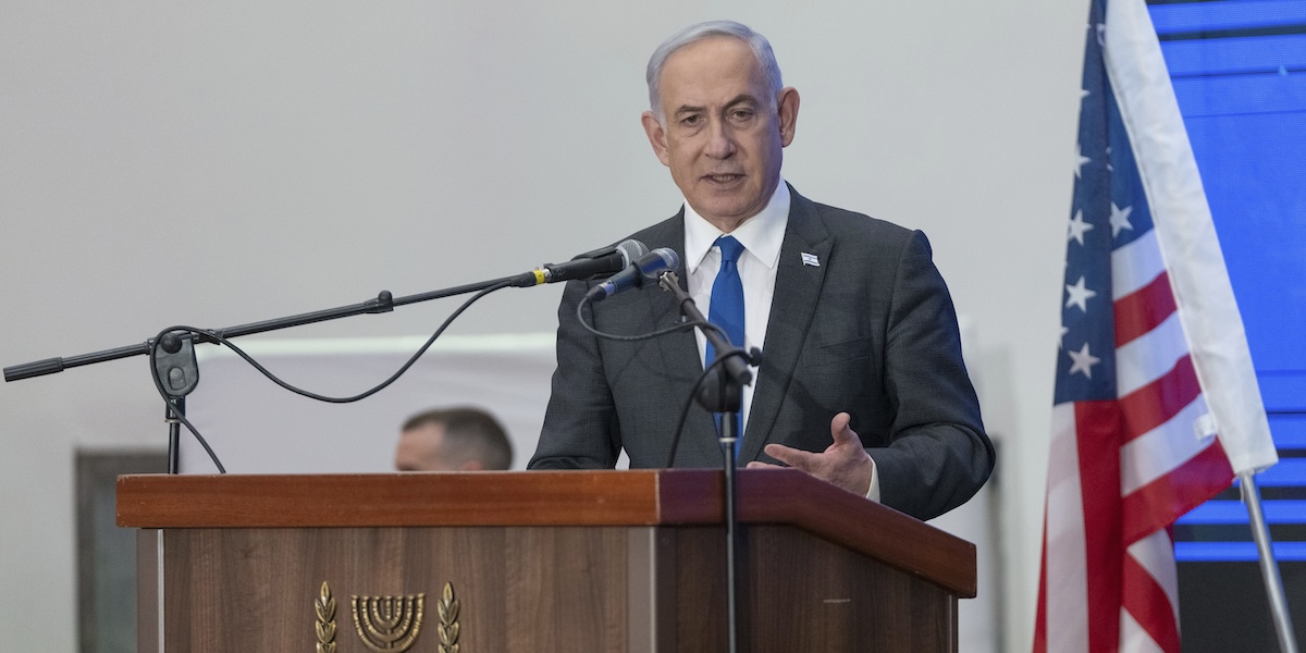 Il primo ministro israeliano Benjamin Netanyahu parla con sullo sfondo una bandiera americana