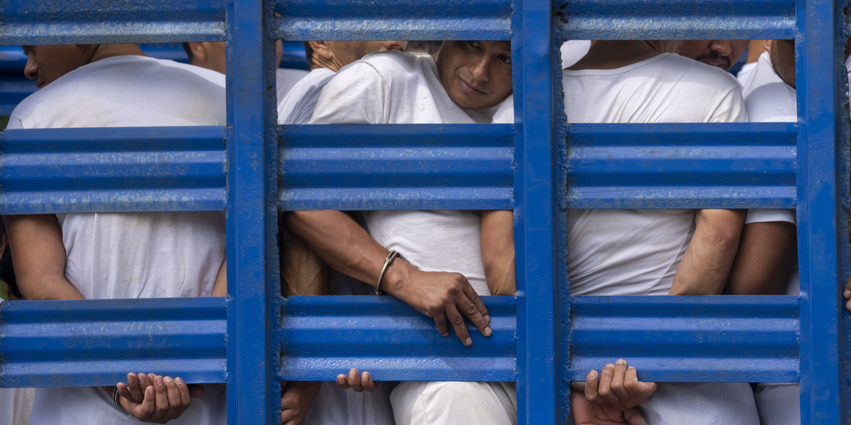 Un gruppo di uomini arrestati viene trasportato verso il centro di detenzione di Soyapango, a El Salvador (AP Photo/Moises Castillo, File)