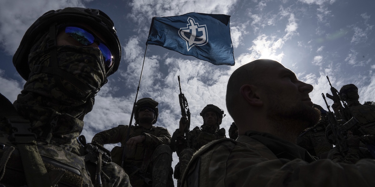 Membri del gruppo militare Corpi di volontari russi, in controluce con una bandiera