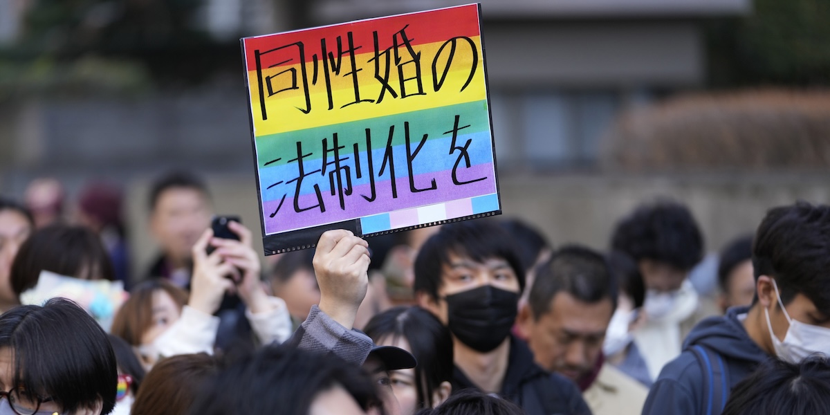 Un uomo fuori dal tribunale di Tokyo mostra un cartello con scritto "Legalizziamo i matrimoni dello stesso sesso"