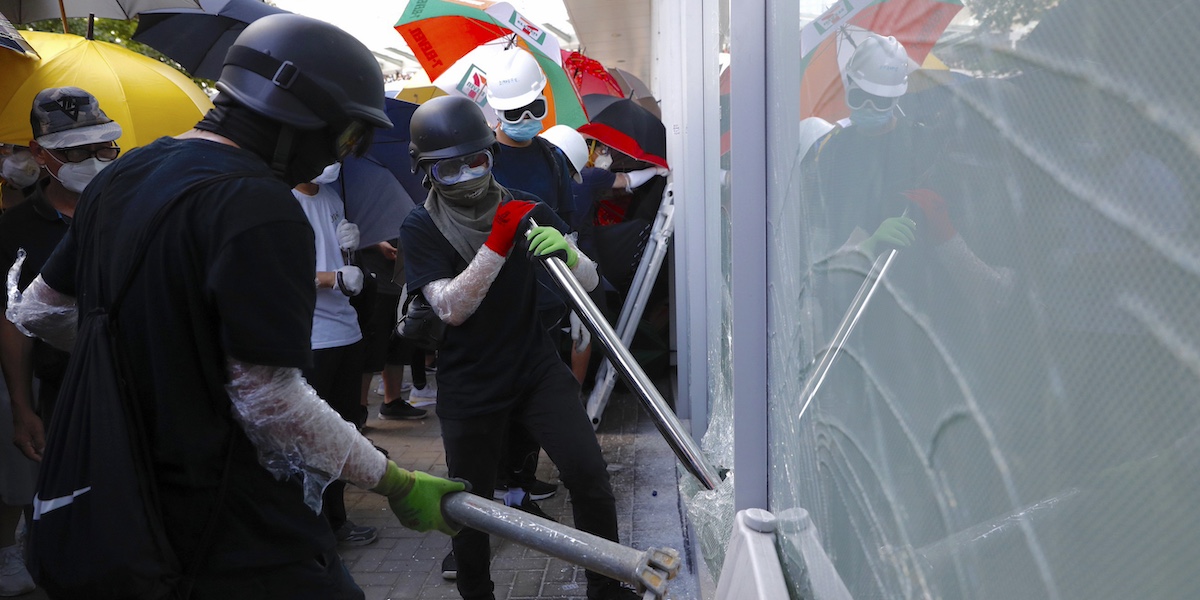 Manifestanti provano a rompere le vetrate della sede del Consiglio legislativo di Hong Kong, il 1° luglio del 2019 (AP Photo/Vincent Yu)