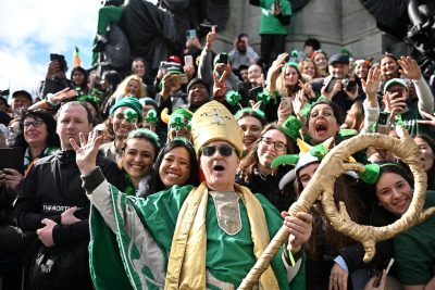 Un uomo che indossa un costume religioso è in posa insieme alle persone che partecipano alla parata di Dublino