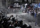 Due file di poliziotti sulla sinistra spruzzano gas lacrimogeno a dei manifestanti durante una protesta antigovernativa contro la scarsità di cibo nelle mense dei poveri e le riforme economiche proposte dal presidente Javier Milei