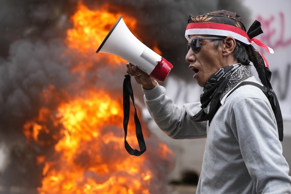 Un uomo grida uno slogan mentre vengono bruciati dei pneumatici durante una manifestazione contro i presunti brogli nelle elezioni presidenziali del 14 febbraio, fuori dall'ufficio della Commissione elettorale generale a Giacarta, Indonesia