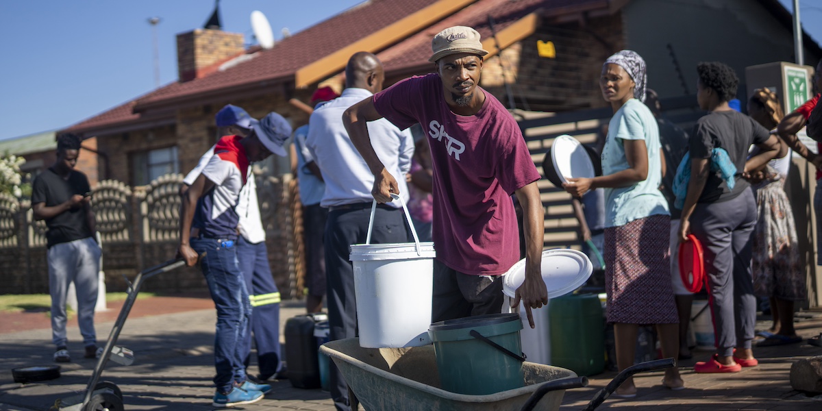 Persone in fila per fare scorta di acqua a Soweto, un quartiere di Johannesburg (AP Photo/Jerome Delay)