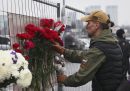 Un uomo mette un fiore rosso sulla recinzione del Crocus City Hall