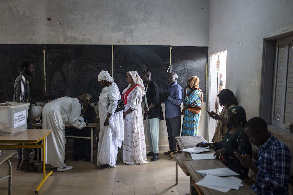 Foto di persone senegalesi in fila per votare in un aula