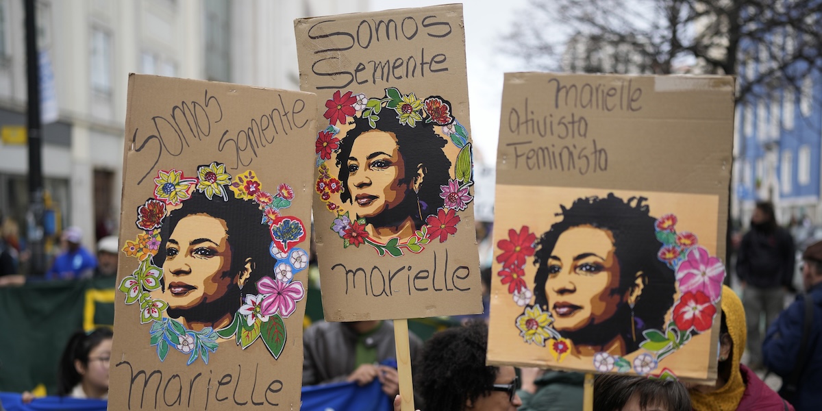 Persone che reggono cartelli con l'immagine stilizzata di Marielle Franco durante una manifestazione antirazzista a Lisbona, in Portogallo, nel 2024