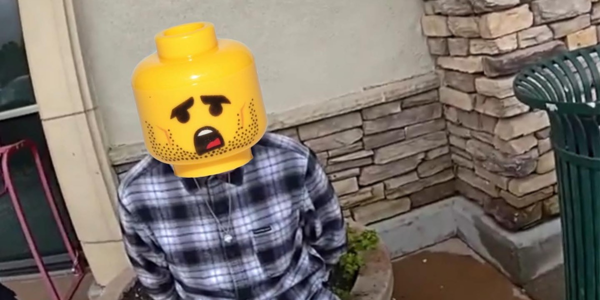 una persona ammanettata con il volto coperto digitalmente con l'immagine di una testa di lego