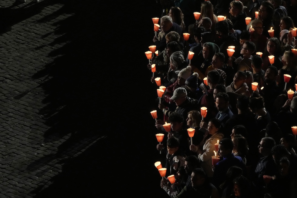 Persone con candele in mano in cammino verso il Colosseo durante la Via Crucis, venerdì sera