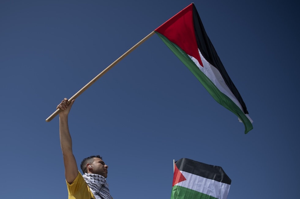 Un uomo sventola una bandiera palestinese durante una manifestazione contro l'operazione militare di Israele nella Striscia di Gaza