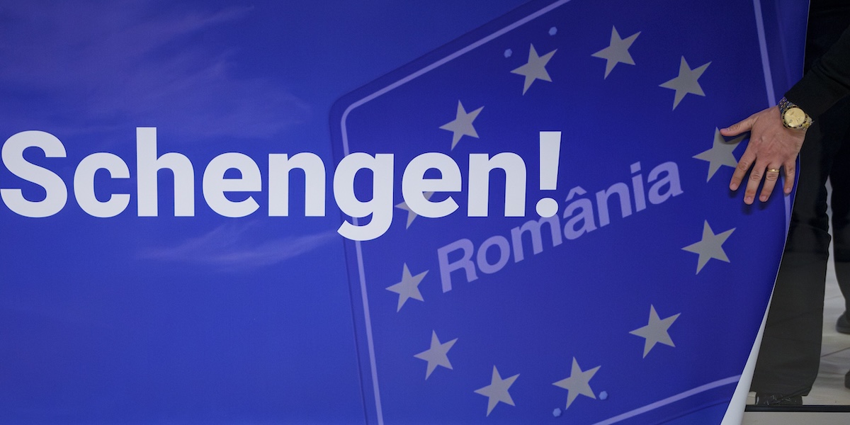 Un uomo tocca un cartellone con scritto "Benvenuti in area Schengen!" all'aeroporto di Otopeni, vicino a Bucarest, in Romania, domenica 31 marzo 2024