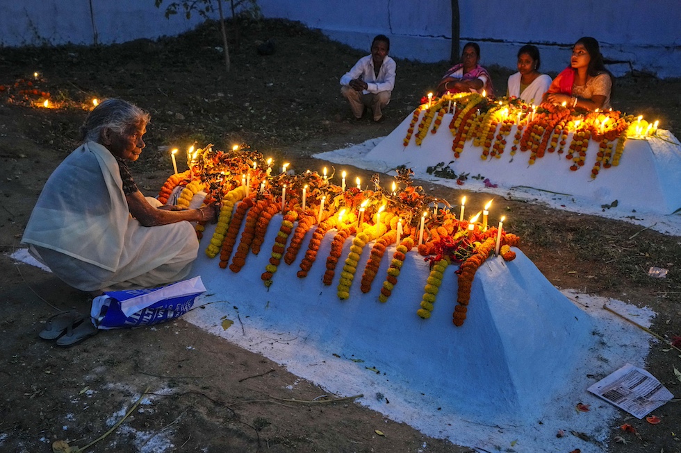 Famiglie cristiane accendono candele e mettono fiori sulle tombe dei loro cari la mattina di Pasqua