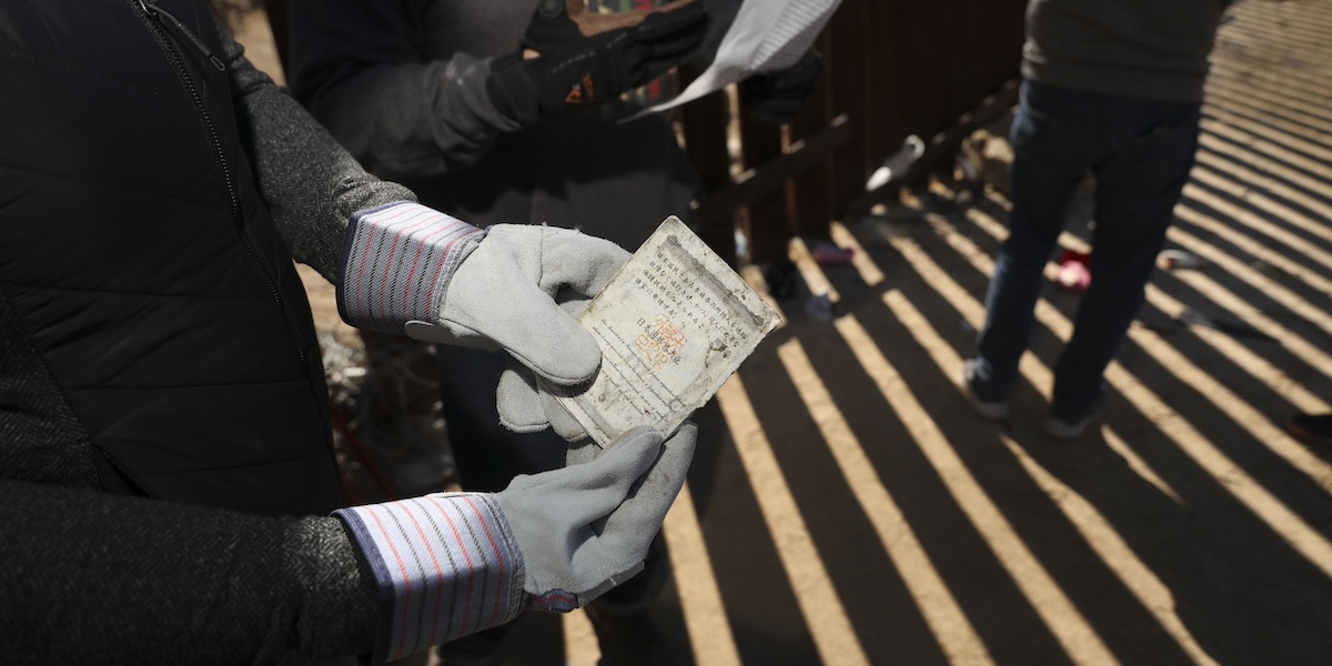 Una persona tiene in mano un passaporto cinese trovato sul muro di confine tra Stati Uniti e Messico il 29 febbraio 2024 in corrispondenza di Jacumba Hot Springs, in California