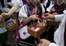 Ragazze che indossano abiti popolari distribuiscono uova decorate durante una tradizionale celebrazione del lunedì dopo Pasqua