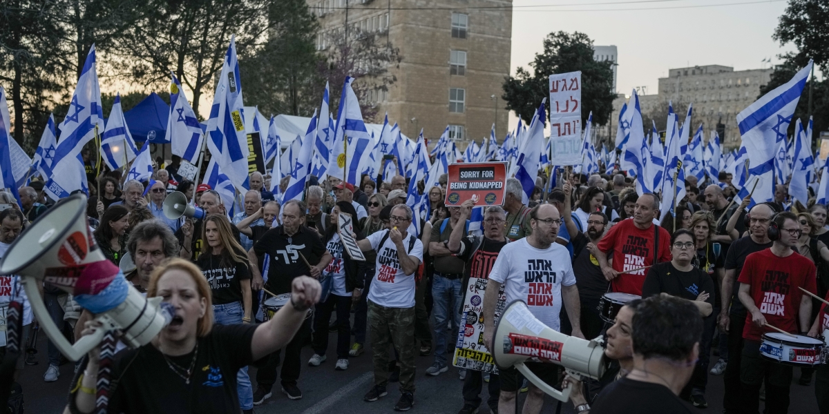 Manifestanti con striscioni e bandiere israeliane fuori dalla Knesset, il parlamento israeliano (AP Photo/Leo Correa)