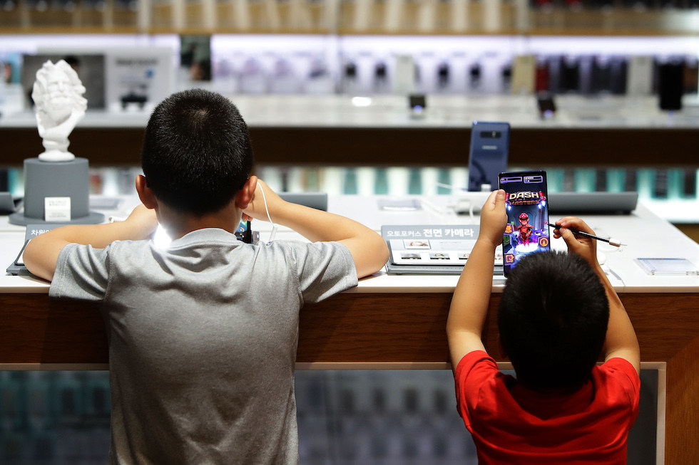 Due bambini maneggiano un tablet e uno smartphone in un negozio di elettronica