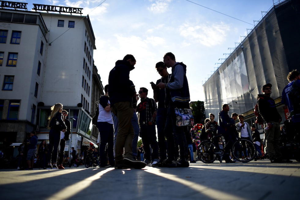 Un gruppo di ragazzi all'aperto con l'attenzione rivolta verso lo schermo di uno smartphone