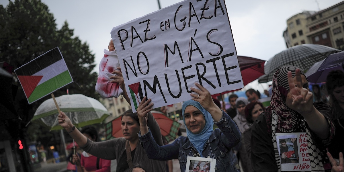 Una donna mostra un cartello che dice "Pace a Gaza. Basta morte" durante una manifestazione a Pamplona, primo agosto 2014