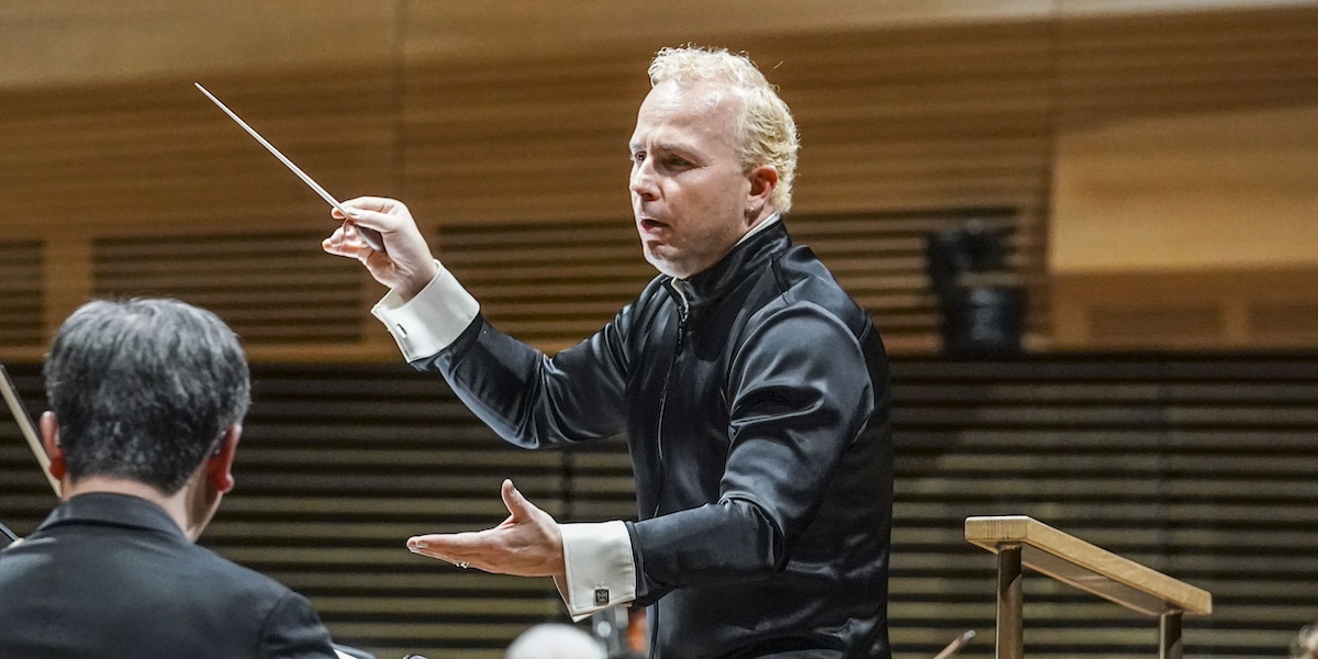 Un direttore in abito nero mentre dirige l'orchestra