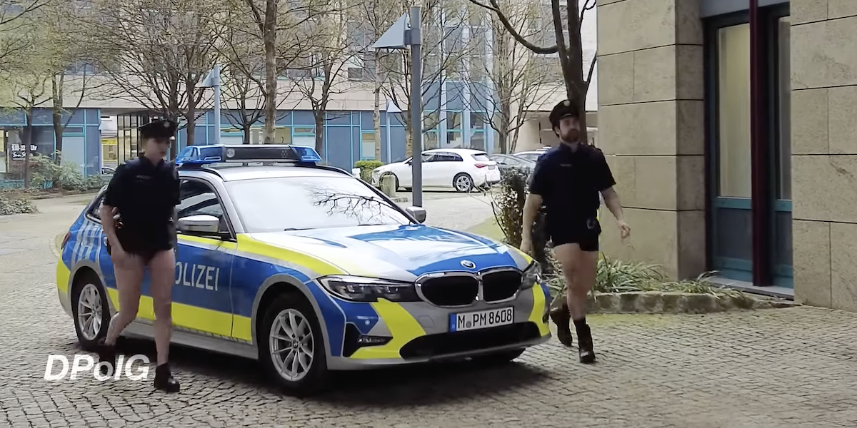 due poliziotti bavaresi scendono da un'auto indossando solo la parte superiore dell'uniforme