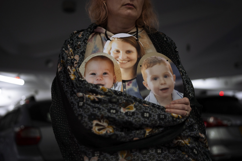 Una donna con le foto di tre ostaggi durante una protesta a Tel Aviv 