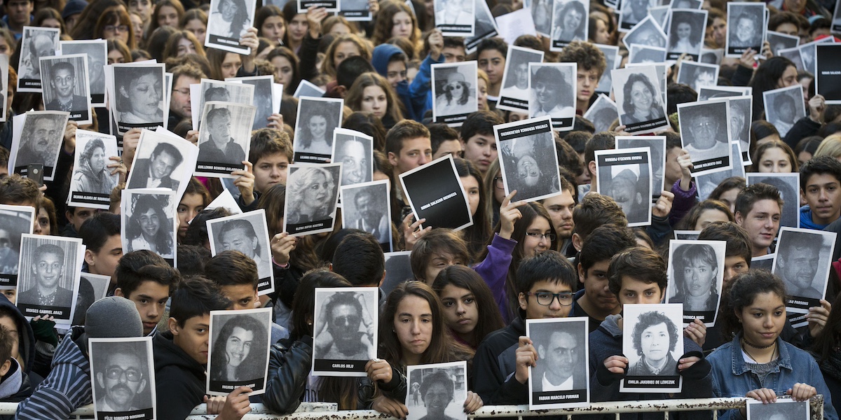 una folla di persone con le foto delle vittime