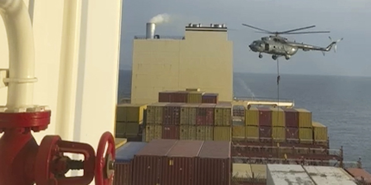 Alcuni uomini si calano da un elicottero sul ponte della nave portacontainer
