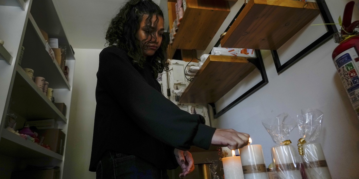 Una donna accende candele per illuminare il suo negozio durante un blackout a Quito, in Ecuador (AP Photo/Dolores Ochoa)
