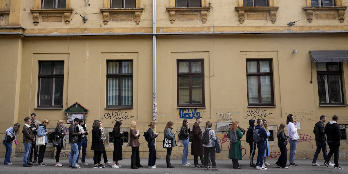 Persone in fila per votare lungo un marciapiede