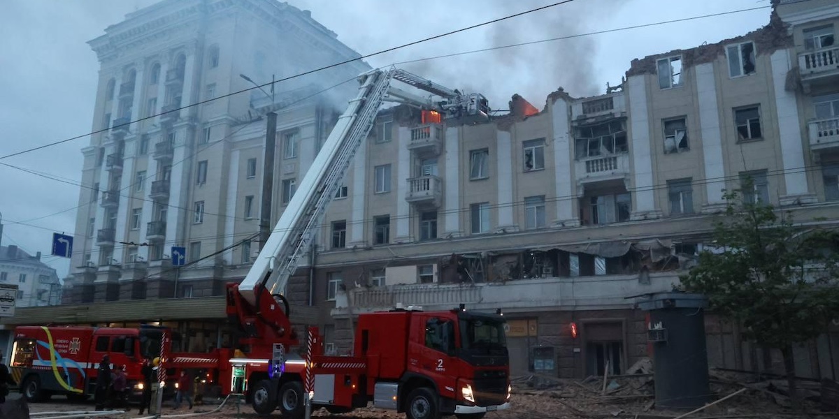 un camion dei vigili del fuoco davanti a un grosso edificio con il tetto distrutto