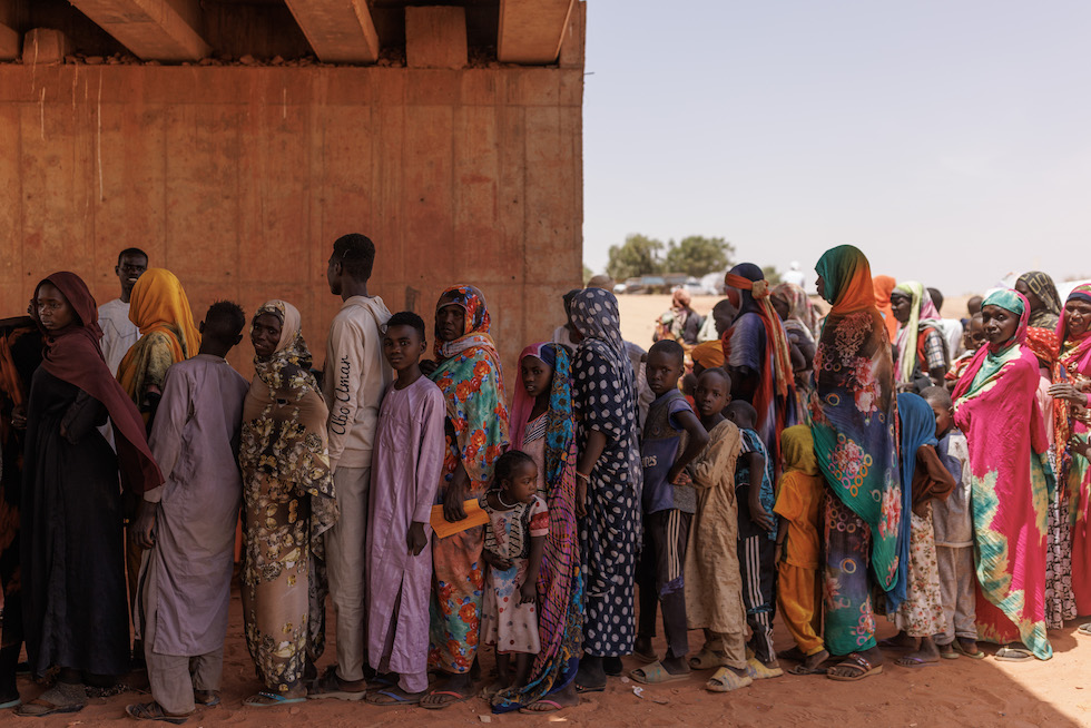 Un gruppo di persone, in fuga dai combattimenti in Darfur, in coda per il controllo dei documenti al confine tra Chad e Sudan