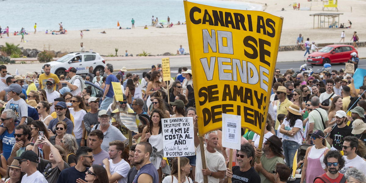 Una folla di persone e cartelloni durante la manifestazione contro il turismo