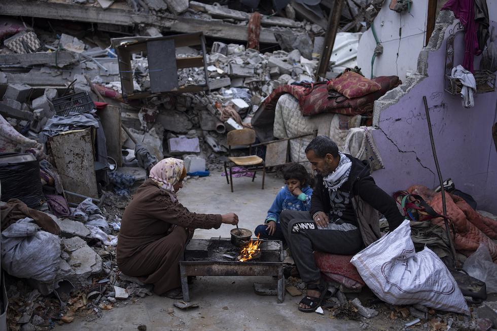Una famiglia prepara da mangiare tra le rovine di alcune abitazioni a Rafah