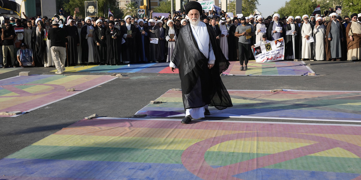 Un seguace del leader politico e religioso sciita Moqtada al Sadr calpesta una bandiera della comunità LGBTQ+, già coperta da un simbolo di divieto, di fronte all'ambasciata svedese a Baghdad, in Iraq, il 30 giugno 2023 (AP Photo/Hadi Mizban)