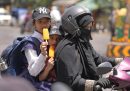 Due bambini mangiano un ghiacciolo mentre vengono portati a scuola dalla madre, durante la grande ondata di calore che da giorni colpisce vari paesi del sudest asiatico (AP Photo/Rajesh Kumar Singh)