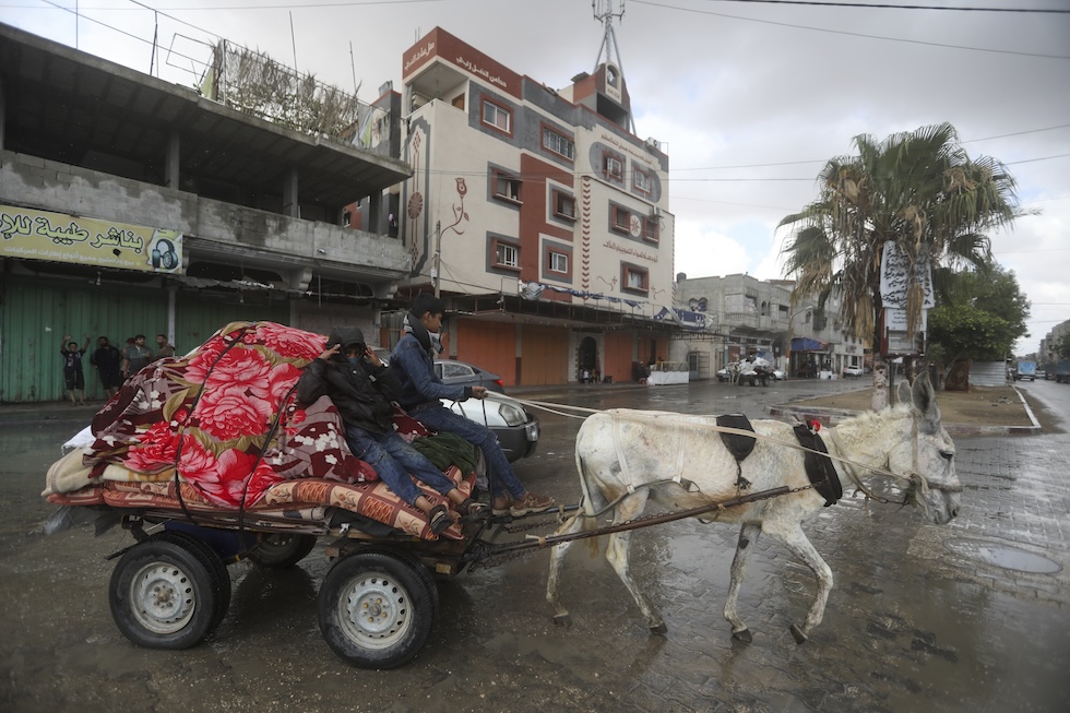 Persone lasciano la città a bordo di un carretto trainato da un asino (AP Photo/ Ismael Abu Dayyah)