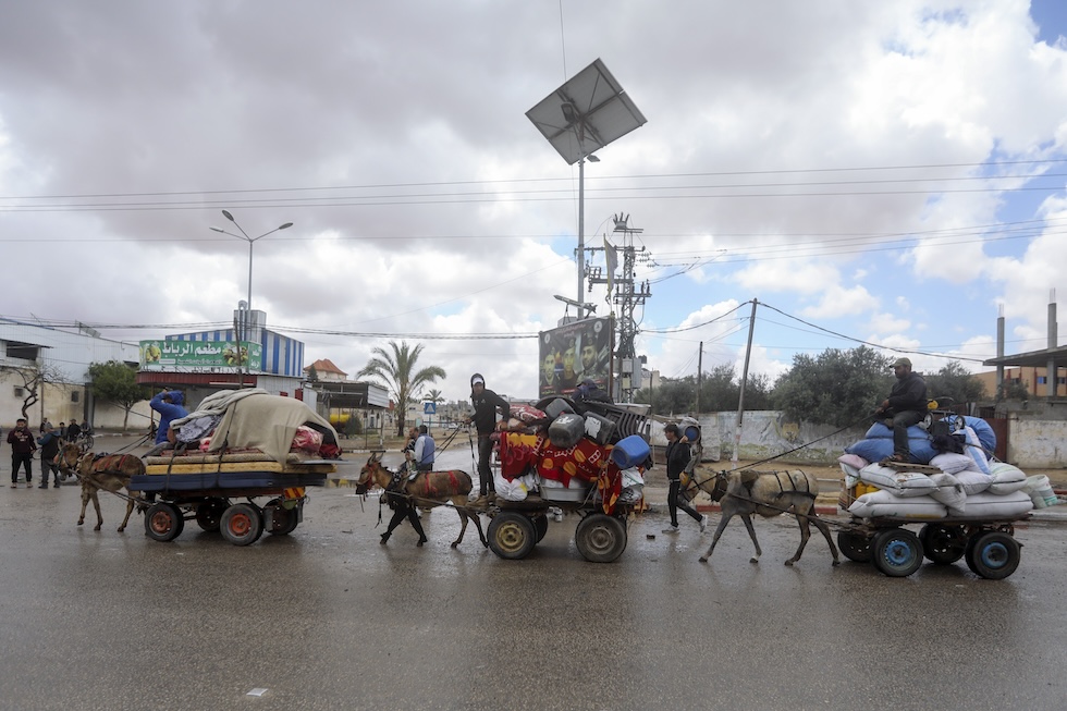 Persone lasciano la città a bordo di un carretto trainato da un asino (AP Photo/ Ismael Abu Dayyah)