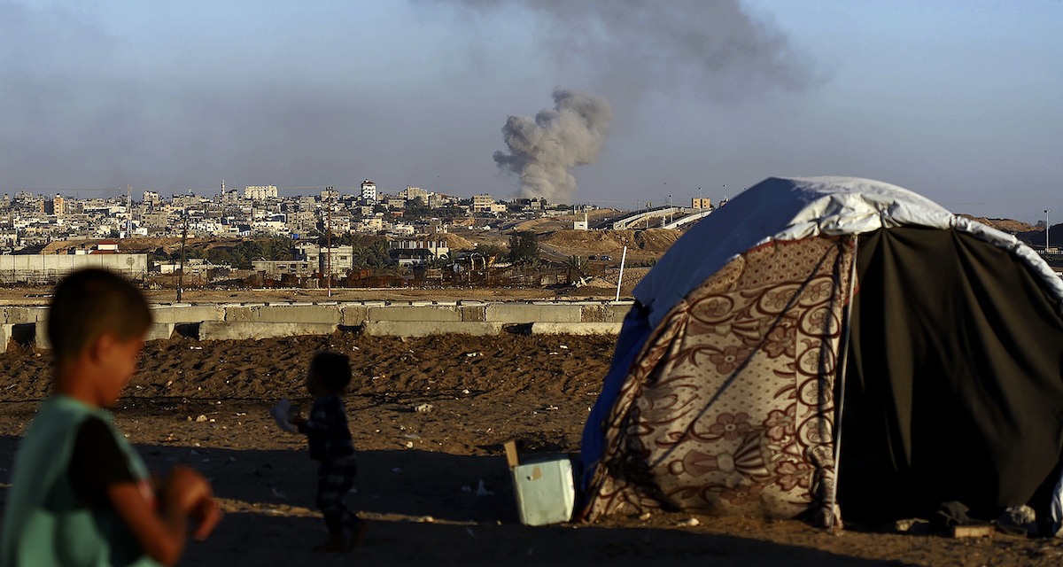 Una tenda montata fuori Rafah, mentre in città si vede il fumo dei bombardamenti, il 7 maggio