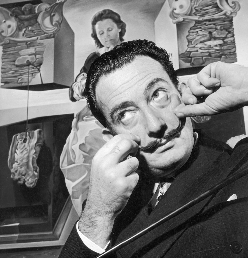 Dalí posa per una foto davanti a un suo dipinto a Londra nel dicembre del 1951 (George Konig/ Keystone Features/ Getty Images)