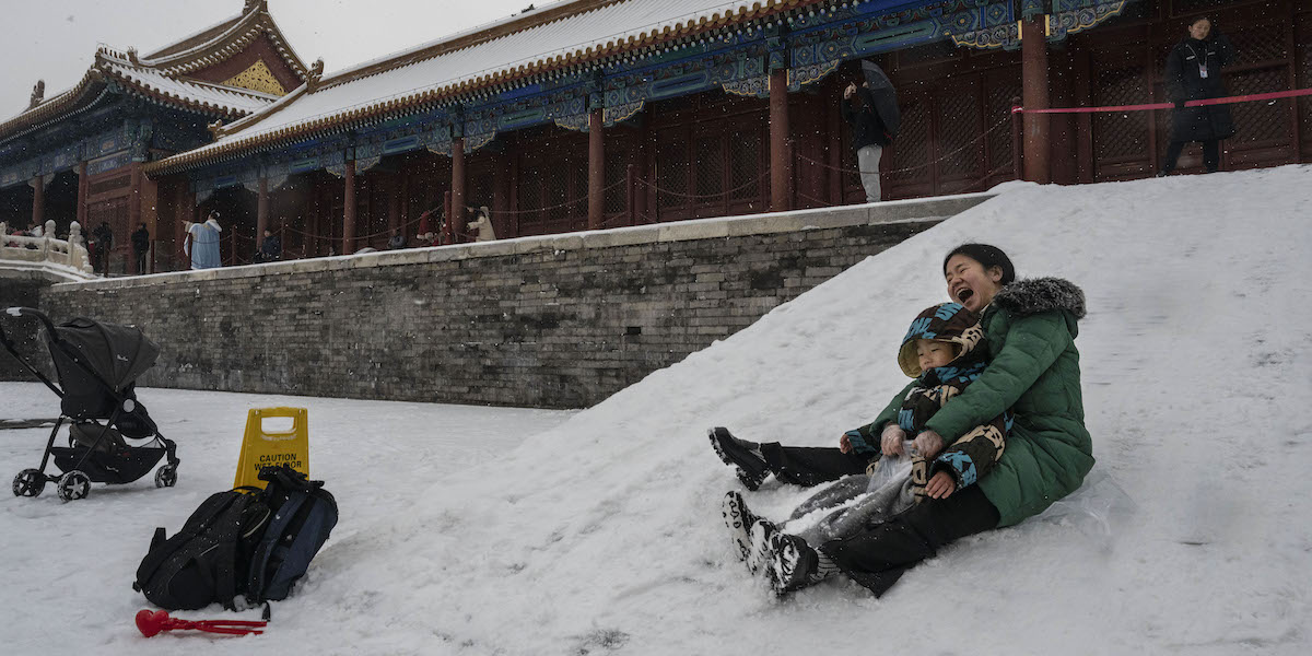 Una mamma gioca con il figlio sulla neve nella Città Proibita, a Pechino (Foto di Kevin Frayer/Getty Images)