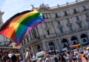 Le persone al Pride e una persona sventola una bandiera arcobaleno