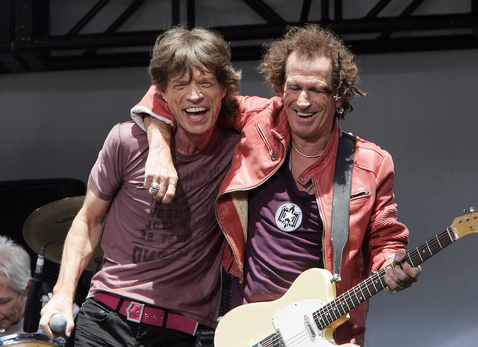 Richards abbraccia Jagger reggendo una chitarra elettrica a tracolla